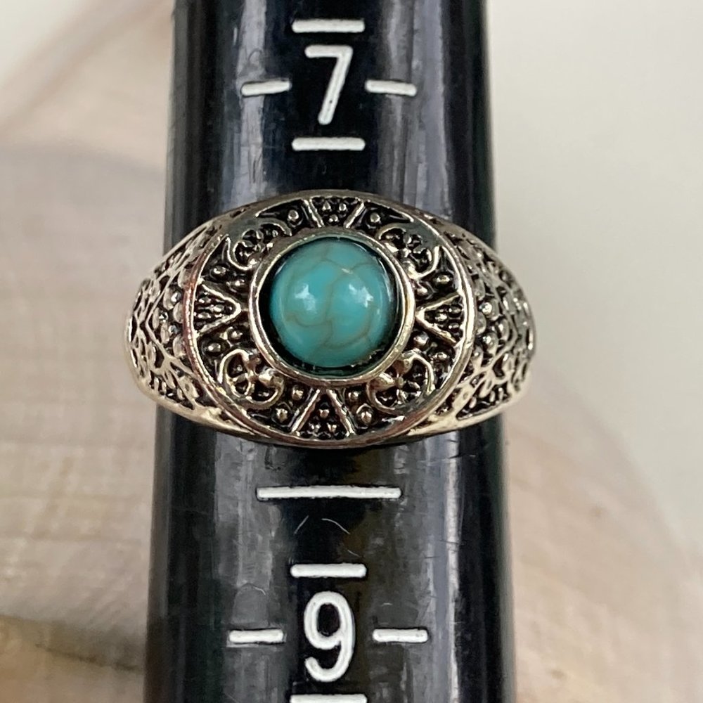 Turquoise-colored gem in silver tone setting ring